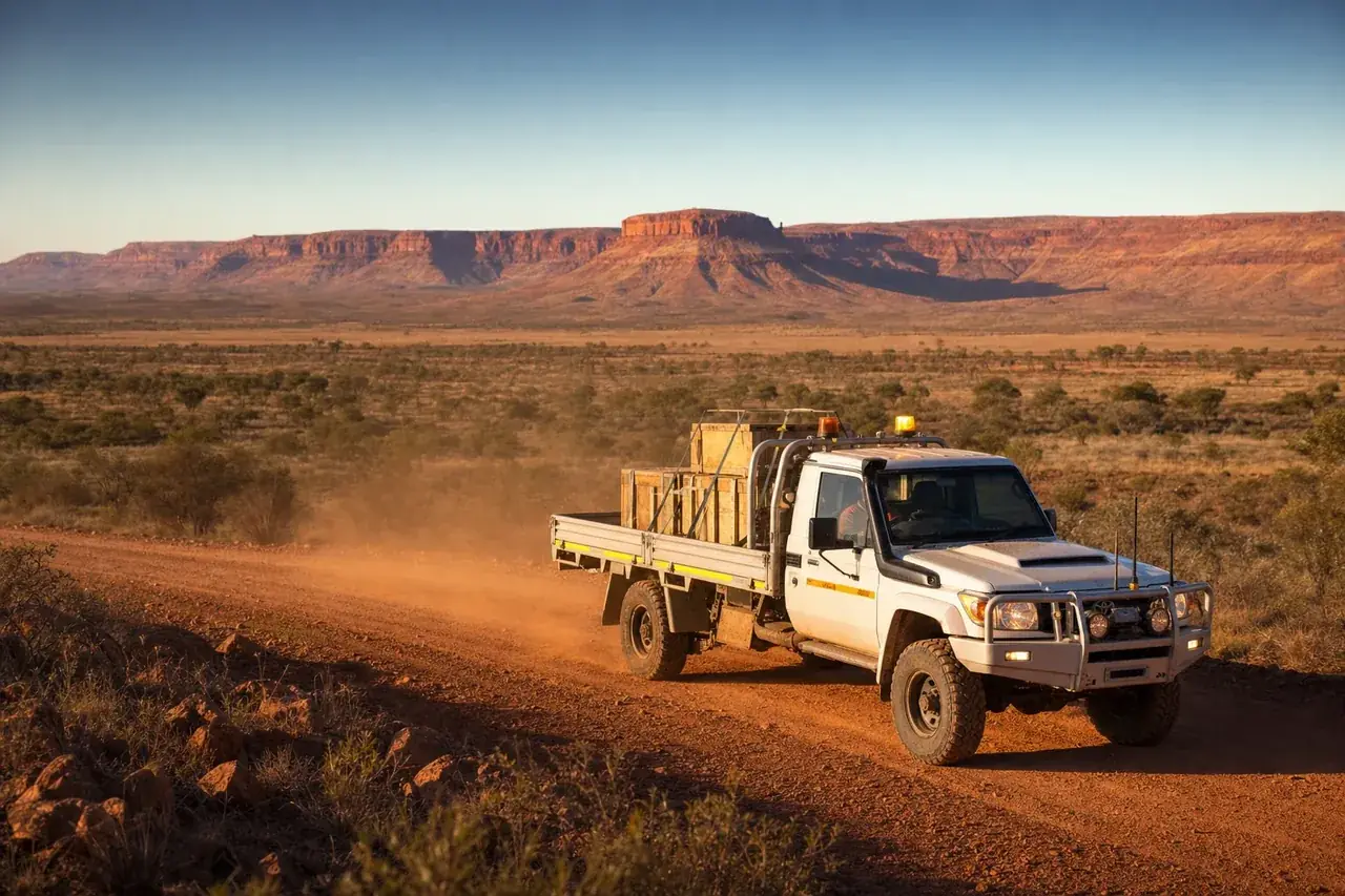 White flatbed hotshot truck carrying crated mining equipment on a red road near Paraburdoo, Pilbara WA
